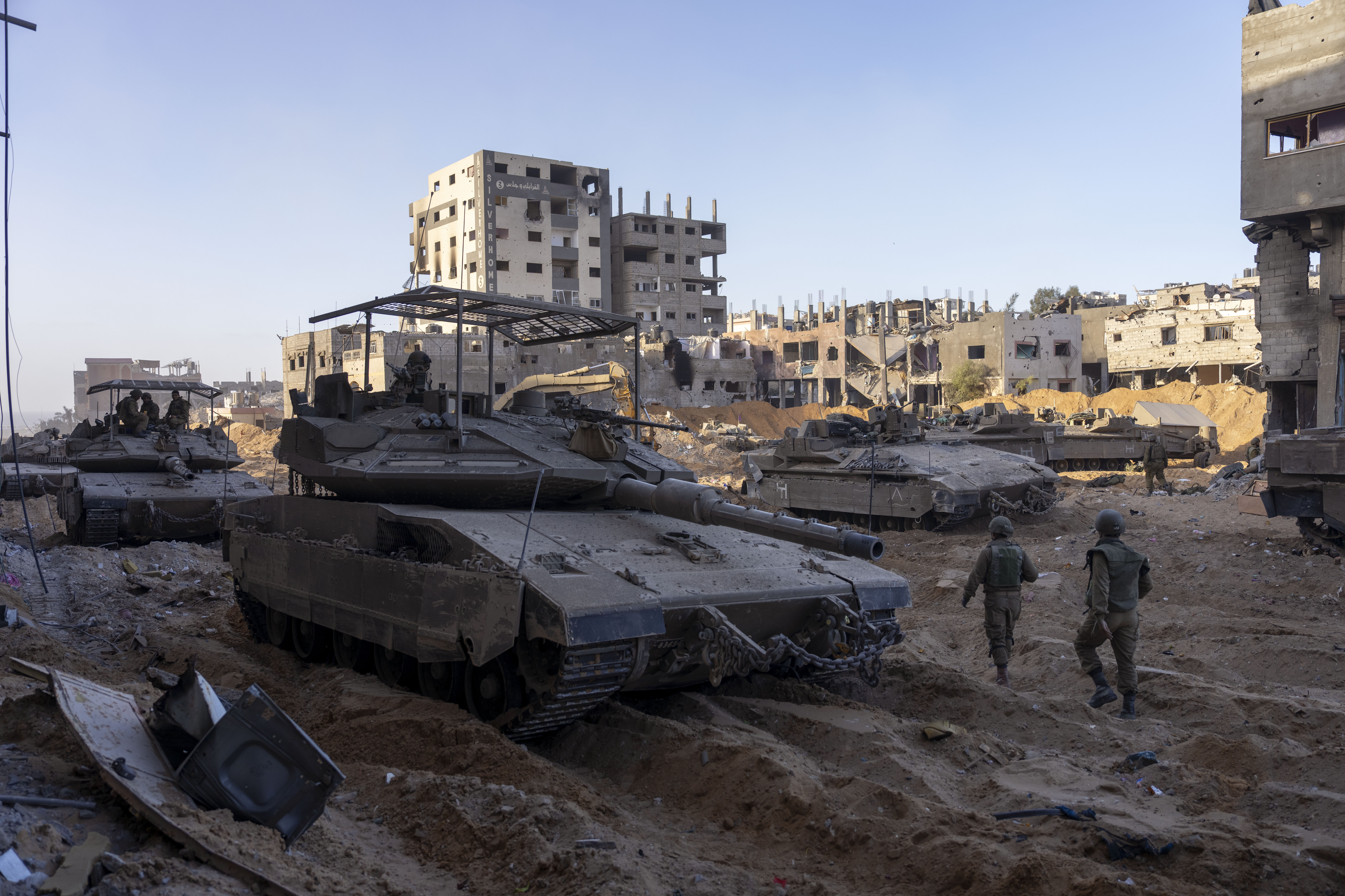 Israeli army troops are seen next to a destroyed building during a ground operation in the Gaza Strip on Wednesday, Nov. 8, 2023.