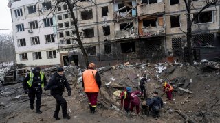 Investigators look for fragments of a rocket inside a crater after a Russian rocket attack at a residential neighbourhood in Kyiv, Ukraine, Wednesday, Dec. 13, 2023.