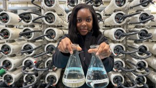 Lakeisha Bryant, public information representative at the Santa Clara Valley Water District, holds flasks of water before and after it is purified at the Silicon Valley Advance Purification Center, Wednesday, Dec. 13, 2023, in San Jose, Calif.