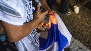A person attempts to burn an Israeli flag