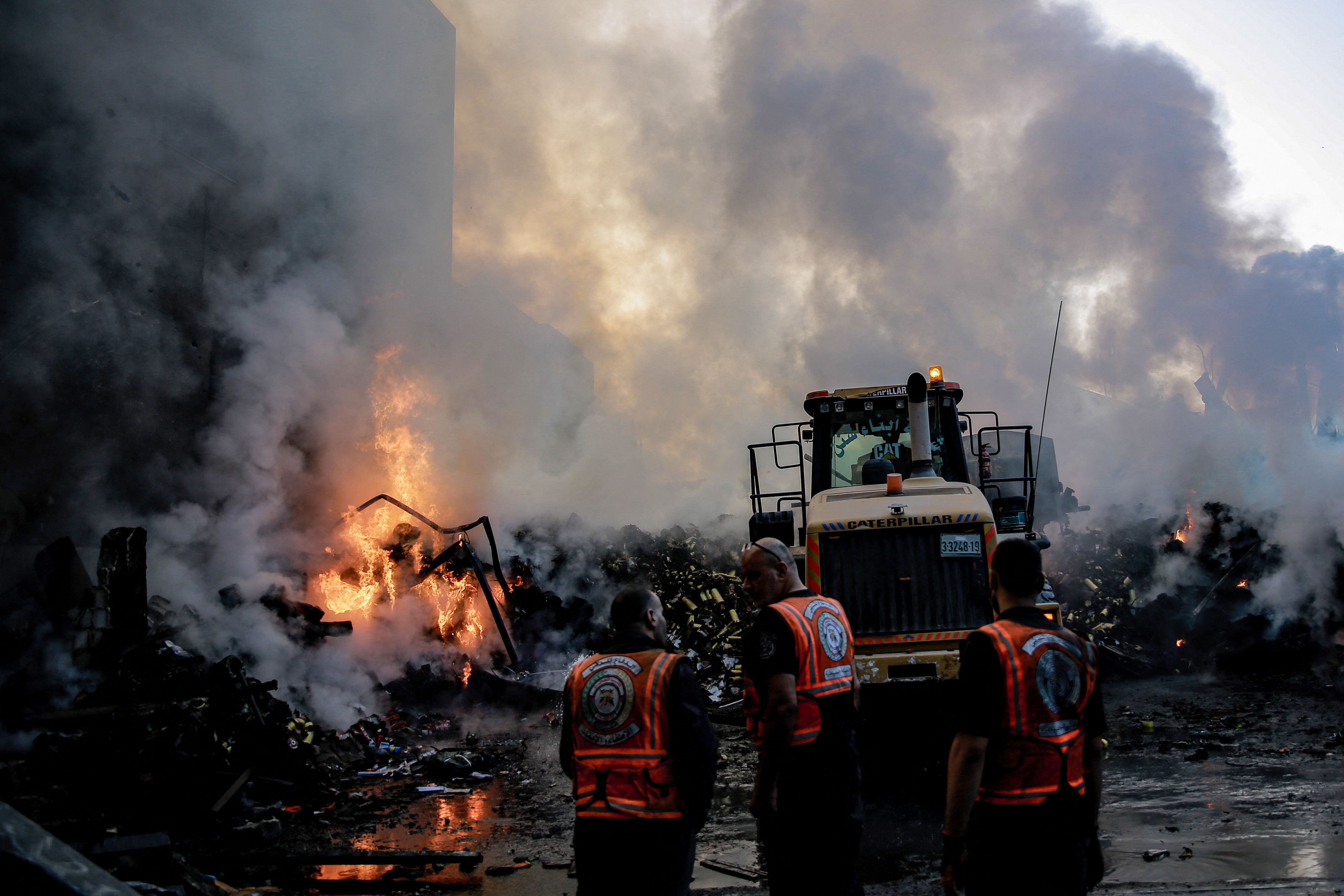 Smoke and fire rise from buildings as rescuers gather amid the destruction in the aftermath of an Israeli strike on Gaza City on October 26, 2023, as battles continue between Israel and the Palestinian Hamas group.