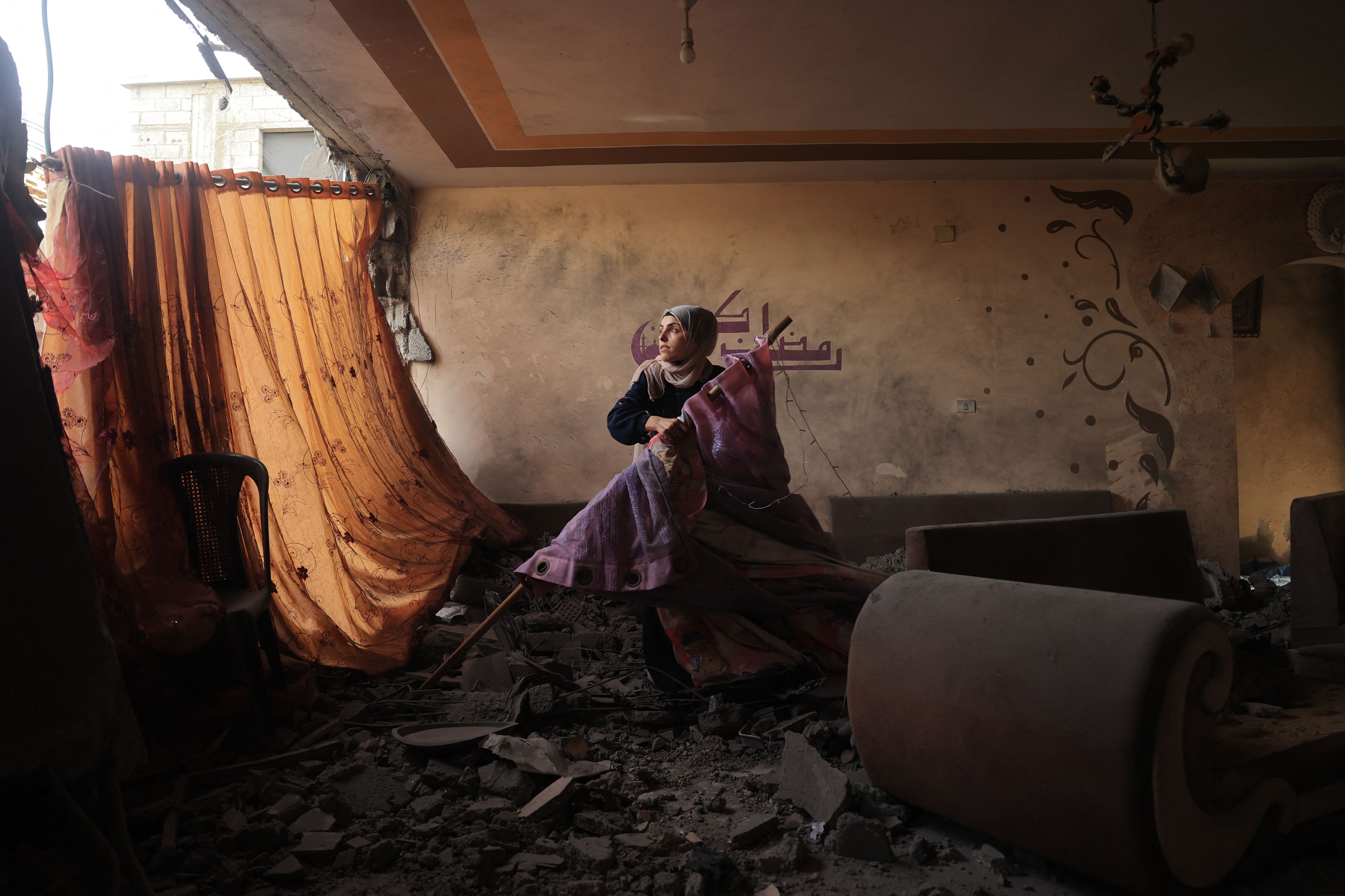 A relative tries to salvage some personal items from the home of the Palestinian Sheikh el-Eed family, a day after it was hit by Israeli bombardment killing the mother and two of her children, in Rafah in the southern Gaza Strip, on November 19, 2023, as battles continue between Israel and the Palestinian militant group Hamas.