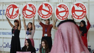 A man wearing a red keffiyeh typical in Saudi Arabia looks on as activists protest against fossil fuels on day ten of the UNFCCC COP28 Climate Conference at Expo City Dubai on December 10, 2023 in Dubai, United Arab Emirates.