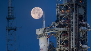 A full moon is seen behind the Artemis I Space Launch System (SLS) and Orion spacecraft, atop the mobile launcher, are prepared for a wet dress rehearsal to practice timelines and procedures for launch, at Launch Complex 39B at NASA's Kennedy Space Center in Florida on June 14, 2022. On Tuesday, Jan. 9, 2024, NASA said astronauts will have to wait until 2025 before flying to the moon and another few years before landing on it.