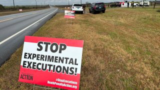 Anti-death penalty activists place signs along the road heading to Holman Correctional Facility in Atmore, Ala.