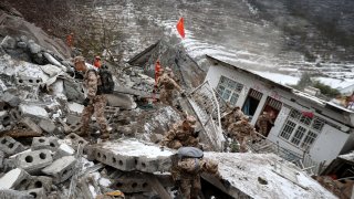 Chinese military personnel and rescue workers search for missing victims following a landslide in southwestern China's Yunnan province.