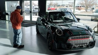 A man looks at a 2024 Cooper S John Cooper Works convertible at a Mini dealership