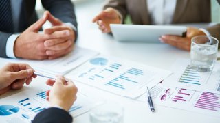 FILE – Image of business documents, pen and glasses on workplace during meeting of partners