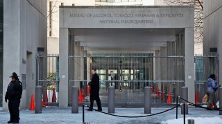 FILE - A security official walks in front of the entrance to the national headquarters of the Bureau of Alcohol, Tobacco, Firearms and Explosives on Jan. 23, 2014, in Washington.