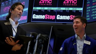 Traders work as a screen displays the trading information for GameStop and AMC Theatres on the floor at the New York Stock Exchange on May 15, 2024.