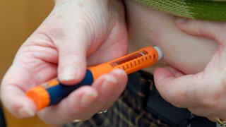 A patient injects herself with an insulin pen.