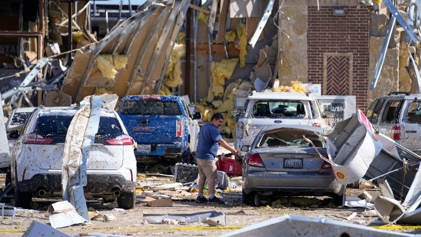 A man looks at a damaged car after a tornado hit the day before