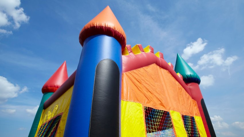 FILE – A children’s inflatable bouncy castle with a blue sky and clouds.