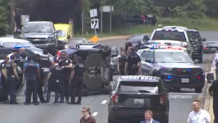 Police are seen gathered around a overturned vehicle in Maryland believed to be associated with a police shooting in D.C.