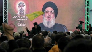 A man waves a Hezbollah movement flag as its leader Hassan Nasrallah delivers a televised speech in Kherbet Selm in southern Lebanon on January 14, 2024, marking the one week memorial since the killing top field commander Wissam Tawil.