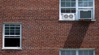 A window air conditioner unit is seen on the side of an apartment building in Arlington, Virginia, July 10, 2023. 