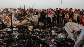 Palestinians look at the destruction after an Israeli strike where displaced people were staying in Rafah, Gaza Strip, Monday, May 27, 2024. Throughout its grinding seven-month war against Hamas, Israel has pledged to investigate a series of deadly events in which its military forces are suspected of wrongdoing. The commitment comes in the face of mounting claims — from human rights groups and the International Criminal Court's chief prosecutor — that the country's leaders are committing war crimes in Hamas-ruled Gaza.