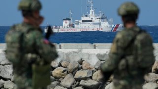 Philippine troops watch a Philippine coast guard ship as they secure an area.