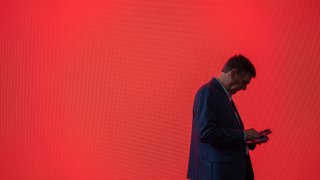 A visitor looks at his phone at the Mobile World Congress 2024 in Barcelona