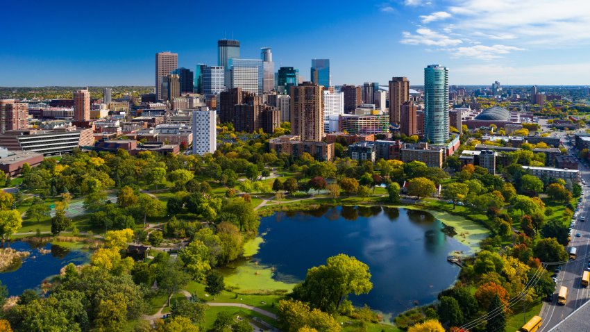 Minneapolis aerial with Downtown Minneapolis skyline in the background and Loring Park with Loring Pond in the foreground, during early autumn.