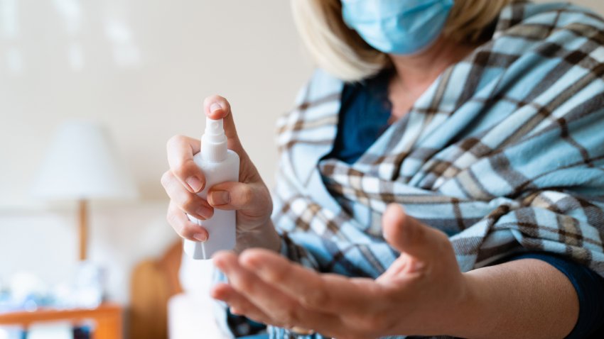 Isolated woman using disinfectant spray to clean her hands.