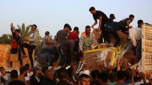 Palestinians climbing onto trucks to grab aid delivered
