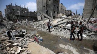 Palestinians are walking past debris a day after an operation by the Israeli Special Forces