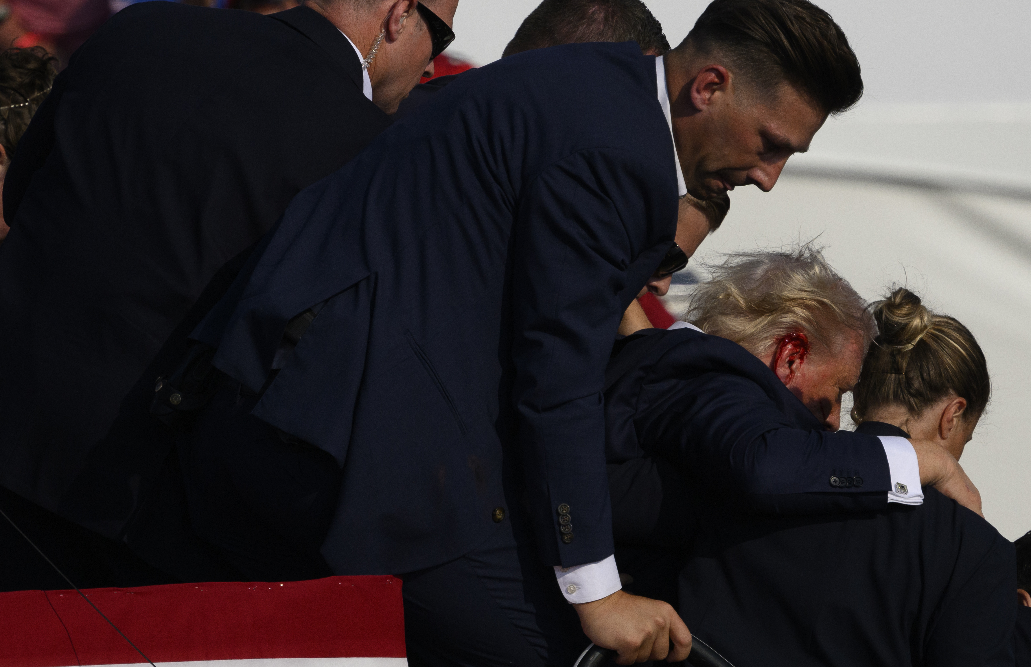 Secret Service agents surround Republican presidential candidate former President Donald Trump onstage after he was injured at a rally on July 13, 2024 in Butler, Pennsylvania.