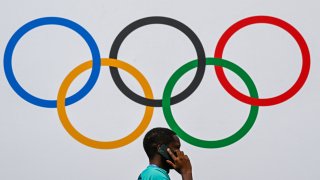 A volunteer speaks on the phone under the Olympics rings at North Paris Arena, the venue for Boxing for the Paris 2024 Olympic Games, in Villepinte, north of Paris, on July 24, 2024.