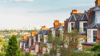 A row of traditional houses on a street in London’s Muswell Hill suburb, located to the north of London, with views of the Canary Wharf on the horizon.