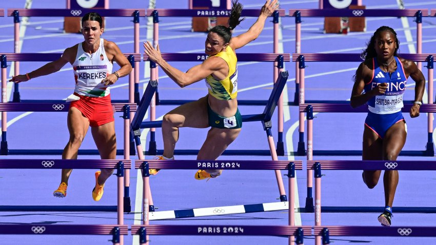 Australia’s Michelle Jenneke falls as Hungary’s Greta Kerekes (L) and France’s Cyrena Samba-Mayela (R) compete in the women’s 100m hurdles heat of the athletics event at the Paris 2024 Olympic Games at Stade de France in Saint-Denis, north of Paris, on August 7, 2024. (Photo by Martin  BERNETTI / AFP) (Photo by MARTIN  BERNETTI/AFP via Getty Images)