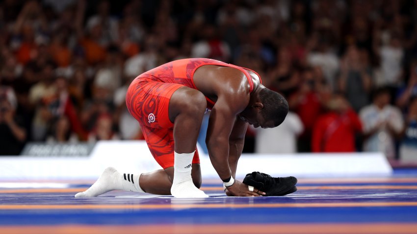 Mijain Lopez Nunez of Team Cuba removes his shoes to signify his retirement following his victory and earning of fifth Olympic Gold during the Wrestling Men's Greco-roman 130kg Gold Medal match against Yasmani Acosta Fernandez of Team Chile (not pictured) on day eleven of the Olympic Games Paris 2024 at Champs-de-Mars Arena on August 06, 2024 in Paris, France.