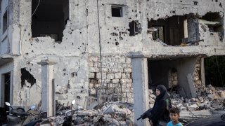 People are seen standing in front of an apartment block destroyed in a recent Israeli strike on August 24, 2024