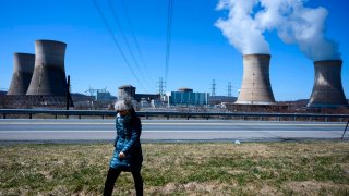 Norma Field walks under power lines coming off of the nuclear plant on Three Mile Island (TMI), with the operational plant run by Exelon Generation, in Middletown, Pennsylvania.