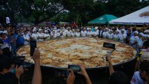 LA PAZ, EL SALVADOR - NOVEMBER 13: Salvadoran cooks poses for a photo with the most gigantic pupusa in the world, during the 18th Festival of the Pupusa in the municipality of Olocuilta in La Paz, El Salvador, on November 13, 2022. Since 2005, the "National Pupusa Day" is celebrated on the second Sunday of November, an iconic food of El Salvador. This year, the giant pupusa prepared in Olocuilta measures 5.5 meters, surpassing the 4.25 meters of 2021, which positioned this municipality as the makers of the largest pupusa in the world recognized by Guinness World Records. (Photo by Alex Pena/Anadolu Agency via Getty Images)