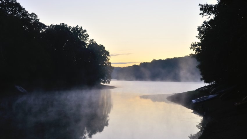 Almost sunrise at the Triadelphia  reservoir in central Maryland. Canoes and kayaks line the shore and the dawn sky reflects in the water with a little mist hanging in the air