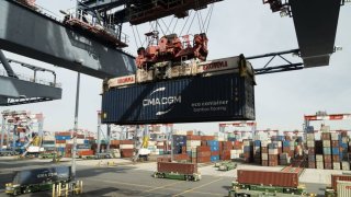 A gantry crane loads containers onto automated guided vehicles (AGV) at the LBCT container terminal at the Port of Long Beach in Long Beach, California, US, on Thursday, Feb. 16, 2023, part of a 10-year, $2.5 billion redevelopment project.