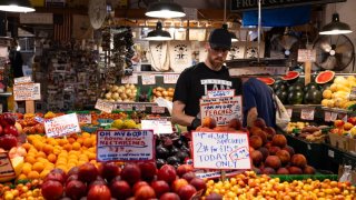 A worker arranges peaches at a fruit stand in the Pike Place Market in Seattle, Washington, US, on Thursday, July 4, 2024. 