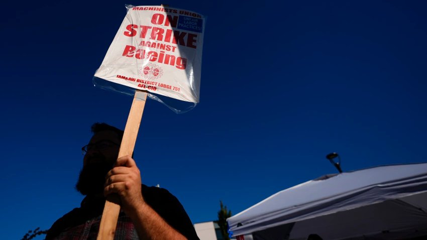 A Boeing worker waves a picket sign Tuesday, Sept. 24, 2024, as workers continue to strike outside the company’s factory in Renton, Wash.