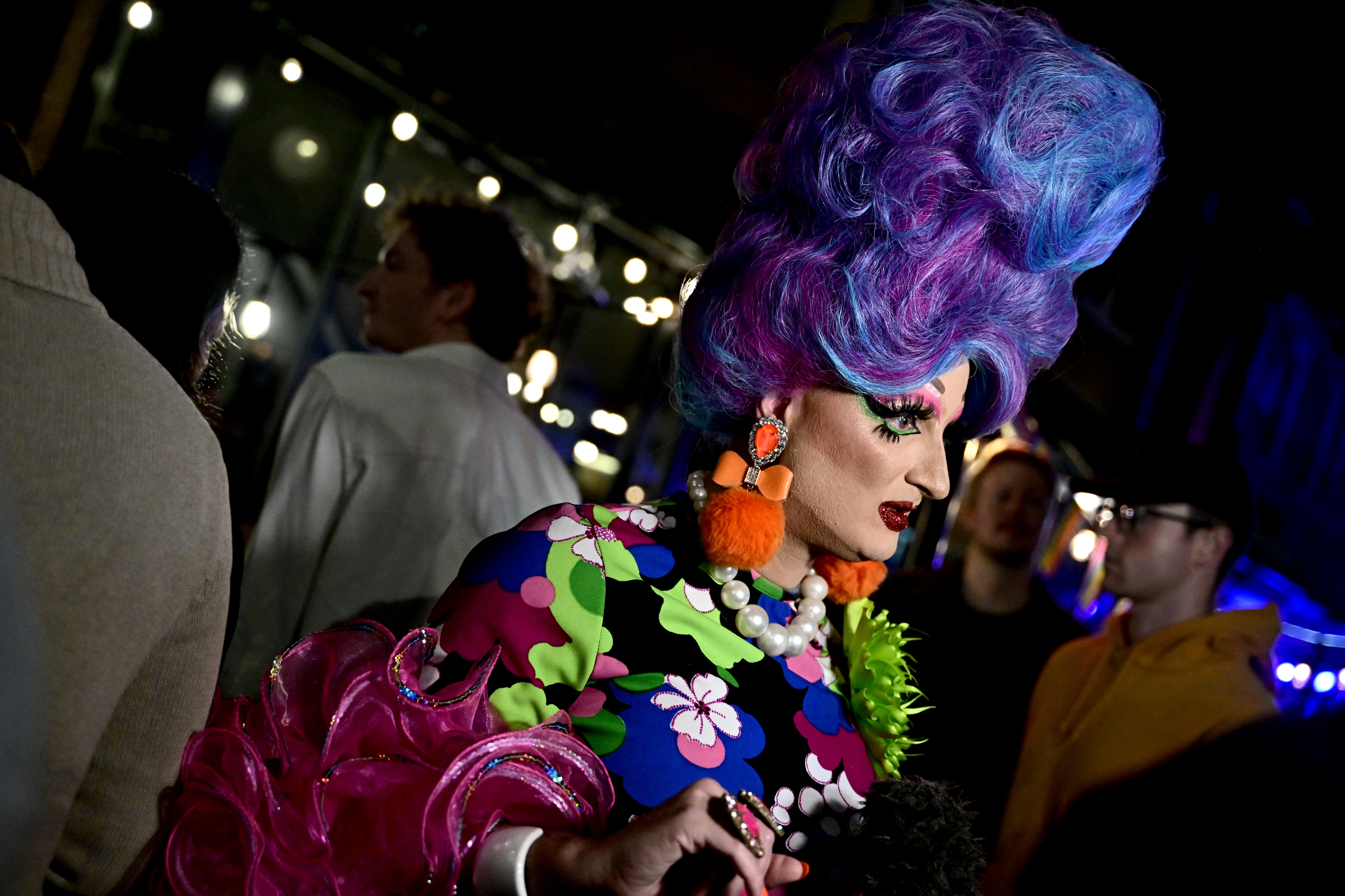 WASHINGTON, DC – OCTOBER 29: A runner wears a mod-inspired costume in a jewel-tone floral print, orange pompom earrings, and a bouffant wig in shades of magenta, purple and blue at the annual 17th Street High Heel Race on October 29, 2024 in Washington, DC. (Photo by Shannon Finney/Getty Images)