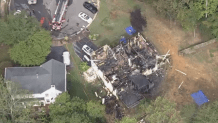 Chopper4 video shows a large, charred structure with a somewhat intact front exterior. However, aerial footage shows the roof and most of the home was destroyed.