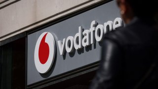 A pedestrian walks past a Vodafone store in central London on May 16, 2023. British mobile giant Vodafone is to axe 11,000 jobs over three years in the latest cull to hit the tech sector, as new boss Margherita Della Valle slammed recent performance.