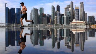 A man jogs along the riverfront with the city skyline pictured in the background at Marina Bay on February 5, 2022 in Singapore.