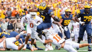 Donovan Edwards #7 of the Michigan Wolverines hurdles a tackle attempt by Michael Taaffe #16 of the Texas Longhorns during the first half of a college football game at Michigan Stadium on September 07, 2024 in Ann Arbor, Michigan. 