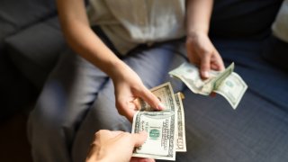 Close-up of woman taking US dollar banknotes from another woman