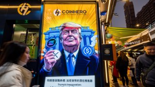 A cartoon image of US President-elect Donald Trump with cryptocurrency tokens, depicted in front of the White House to mark his inauguration, displayed at a Coinhero store in Hong Kong, China, on Monday, Jan. 20, 2025. 