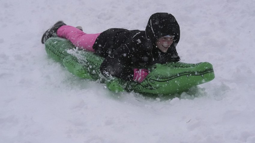 Quin Ogg sleds on the backside of the Mississippi River levee as snow falls in New Orleans, Tuesday, Jan. 21, 2025.