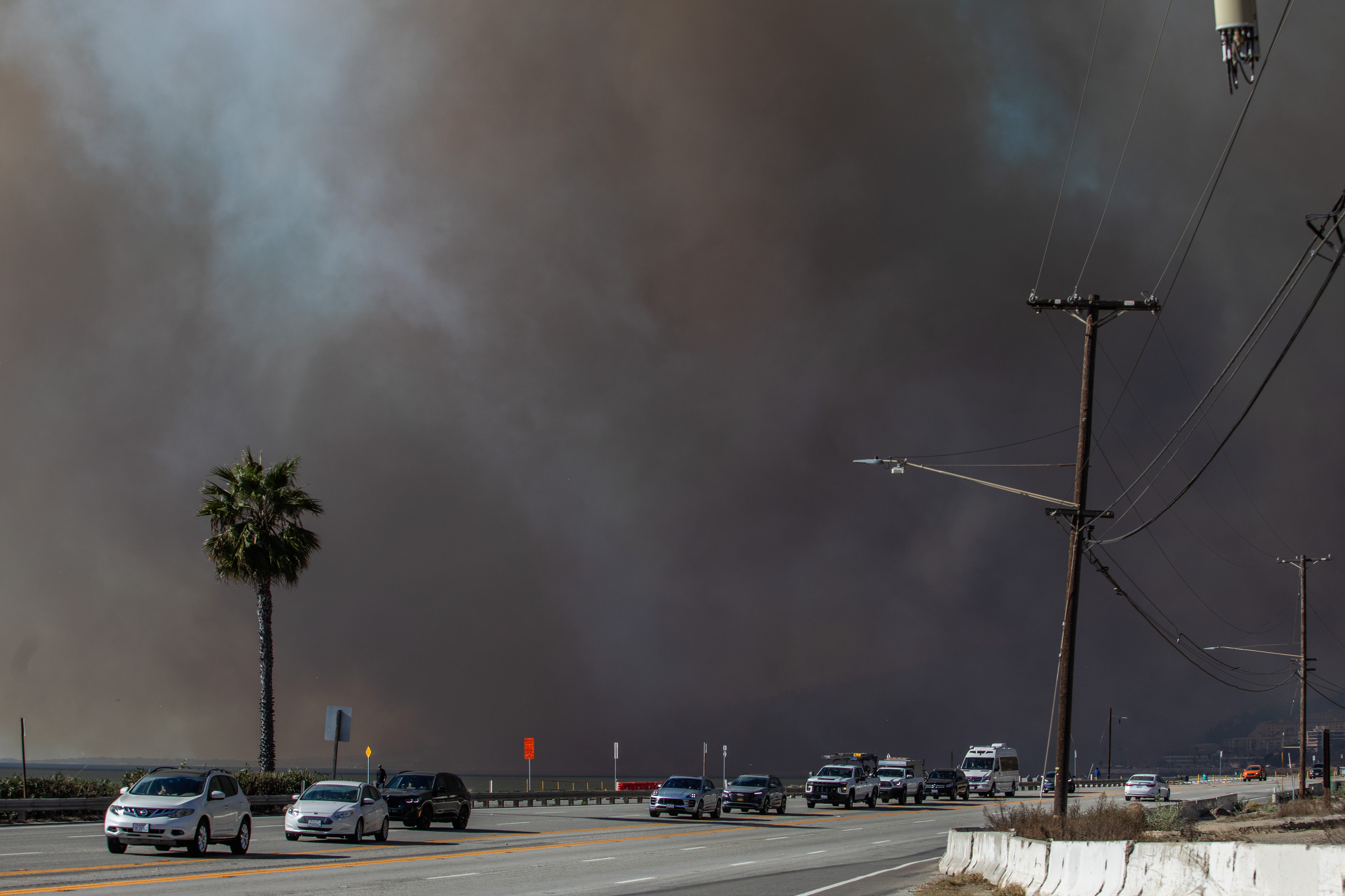 People evacuate along Sunset Boulevard as the Palisades Fire burns amid a powerful windstorm on Jan. 7, 2025 in the Pacific Palisades neighborhood.