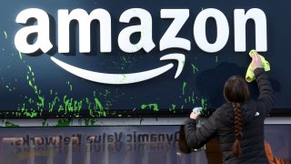 A woman cleans the store window of the Amazon house after activists sprayed paint its facade during a protest on the opening day of the 55th annual meeting of the World Economic Forum in Davos, Switzerland, on Jan. 20, 2025.
