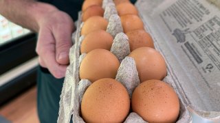 A grocery store owner holds an open carton of eggs in Alameda, Calif., on Tuesday, Feb. 11, 2025.
